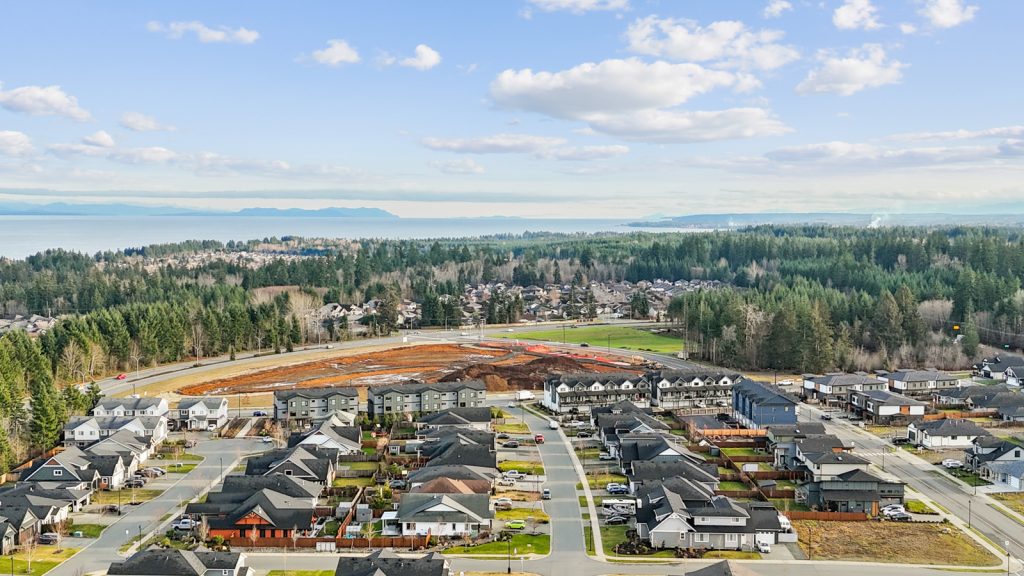 Aerial view of serviced residential lots and homes in Campbell River on Vancouver Island, showing a ready-to-build neighbourhood near forested land.