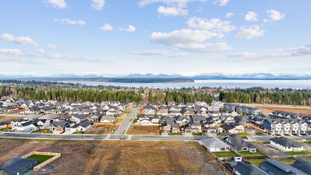Aerial view of a serviced residential neighbourhood on Vancouver Island with completed roads, utilities, and nearby coastline.