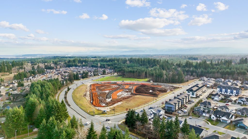 Aerial view of a residential neighbourhood on Vancouver Island with serviced lots, completed roads, utilities, and nearby forested land.