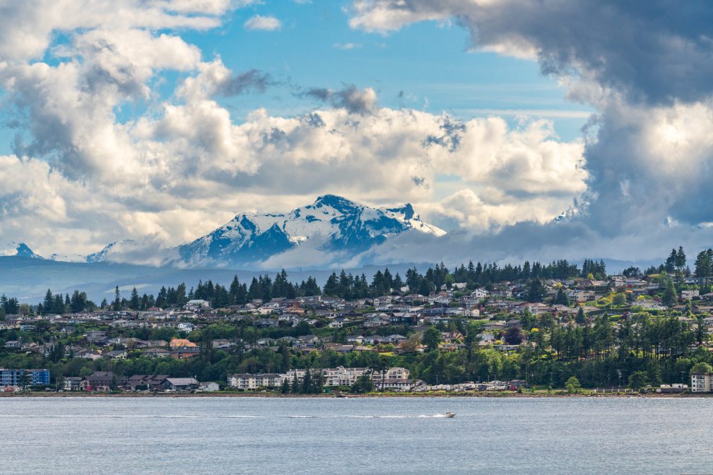 Coastal neighbourhood on Vancouver Island with homes near water and forested hills, illustrating walkable community design.